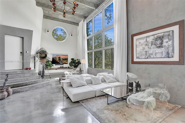 living room featuring a high ceiling, a chandelier, and concrete flooring