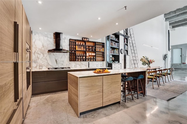 kitchen with a kitchen breakfast bar, a center island, wall chimney exhaust hood, and stainless steel appliances