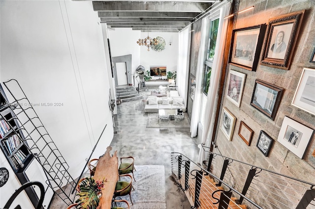 hallway with concrete flooring, a chandelier, and a towering ceiling