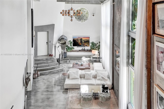 interior space featuring concrete floors, a notable chandelier, and a towering ceiling