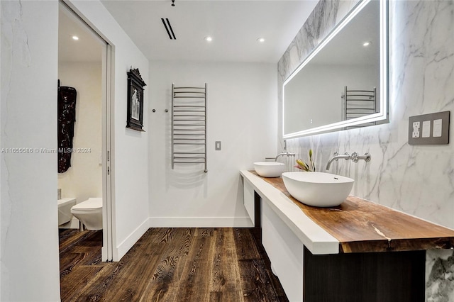 bathroom featuring toilet, vanity, a bidet, wood-type flooring, and decorative backsplash