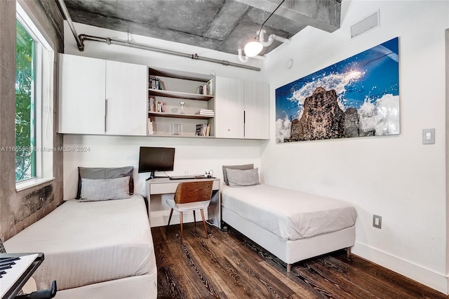 sitting room featuring a wealth of natural light, built in desk, and dark hardwood / wood-style flooring