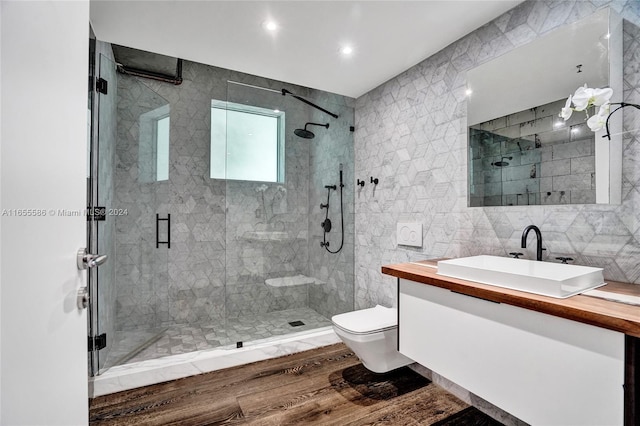 bathroom with toilet, an enclosed shower, vanity, wood-type flooring, and tile walls