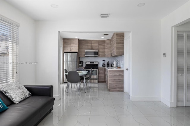 interior space with tasteful backsplash, stainless steel appliances, and sink