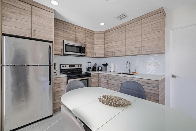 kitchen with backsplash, sink, and appliances with stainless steel finishes