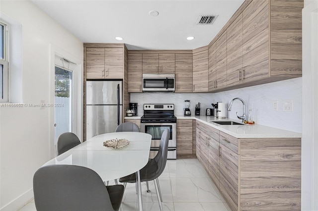 kitchen featuring sink, appliances with stainless steel finishes, and decorative backsplash