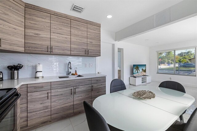 kitchen featuring electric range, decorative backsplash, and sink