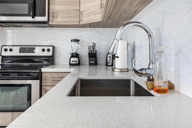 kitchen featuring appliances with stainless steel finishes, light stone countertops, and sink