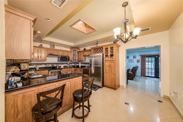 kitchen featuring an inviting chandelier, stainless steel appliances, kitchen peninsula, pendant lighting, and decorative backsplash