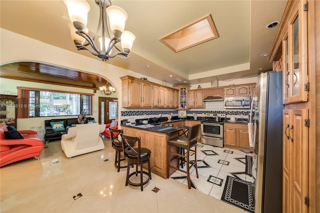 kitchen featuring backsplash, light tile patterned floors, an inviting chandelier, stainless steel appliances, and a breakfast bar