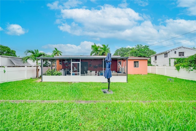 back of house featuring a lawn and a sunroom