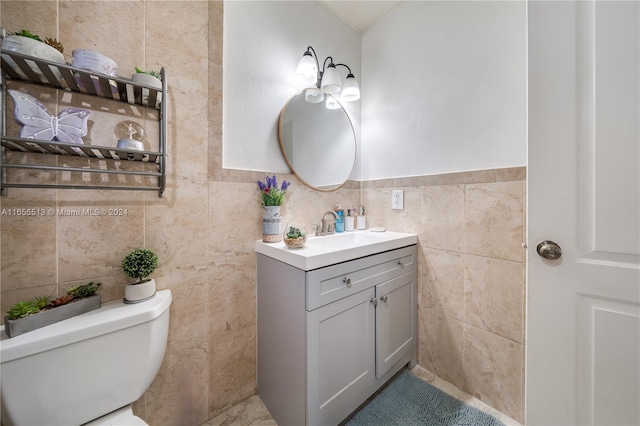 bathroom with vanity, toilet, and tile walls