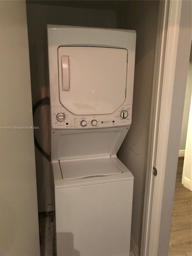 clothes washing area with wood-type flooring and stacked washer / drying machine