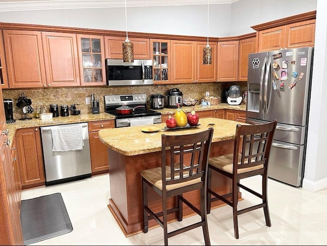 kitchen featuring tasteful backsplash, a kitchen island, light stone countertops, hanging light fixtures, and appliances with stainless steel finishes