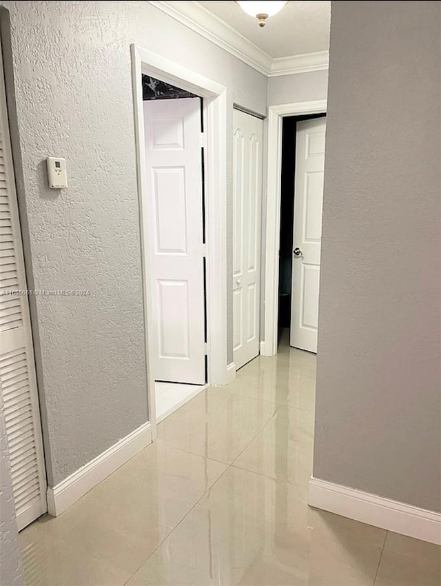 hallway featuring ornamental molding and light tile patterned flooring