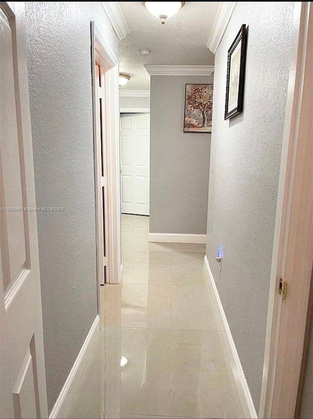 hall with ornamental molding, light tile patterned flooring, and a textured ceiling