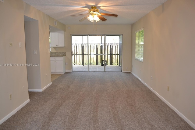 carpeted spare room featuring a textured ceiling and ceiling fan