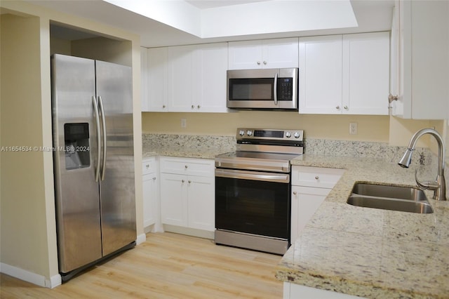 kitchen featuring light hardwood / wood-style flooring, light stone counters, stainless steel appliances, white cabinetry, and sink