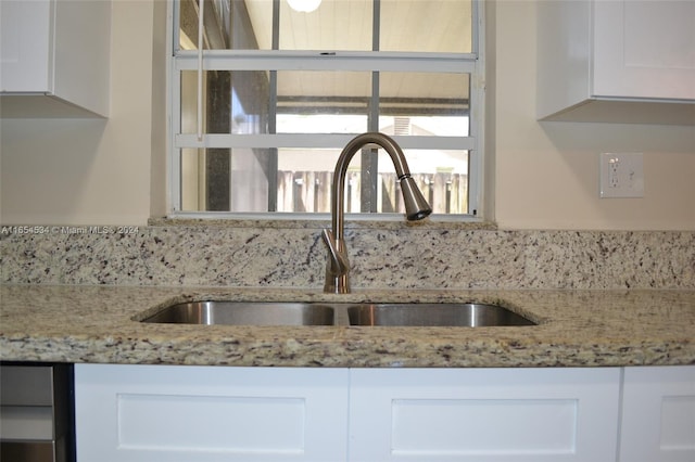 room details with sink, light stone countertops, and white cabinets