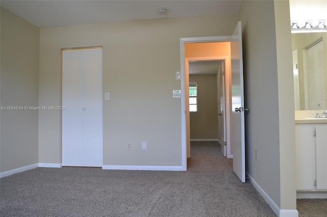 unfurnished bedroom featuring carpet, a textured ceiling, and ensuite bathroom