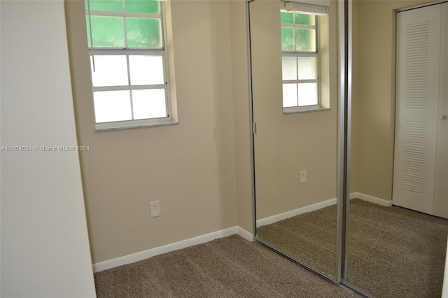 unfurnished bedroom featuring multiple windows, a closet, and carpet