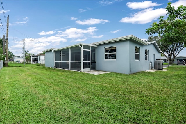 rear view of house featuring central AC unit, a lawn, and a sunroom