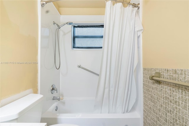 bathroom featuring tile walls, toilet, and shower / bath combination with curtain