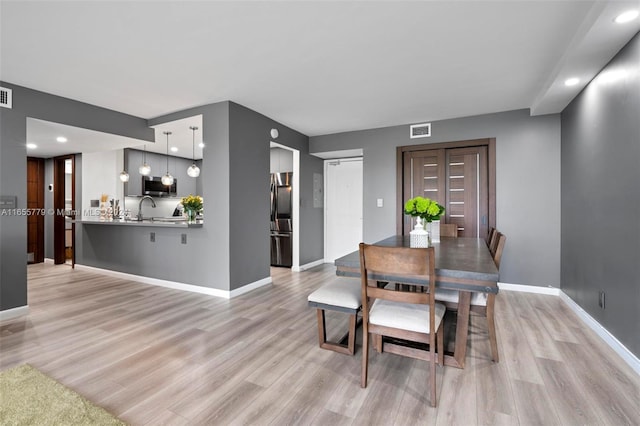 dining area with light wood-type flooring and sink