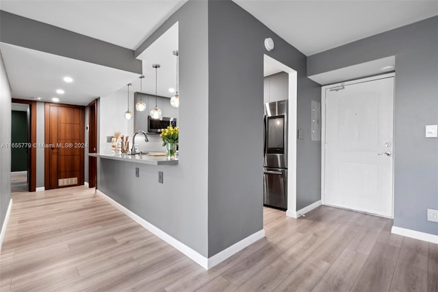 kitchen with electric panel, light hardwood / wood-style flooring, appliances with stainless steel finishes, and hanging light fixtures