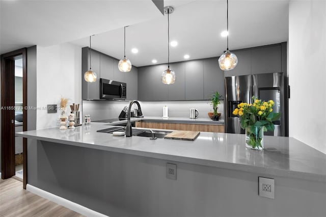 kitchen featuring gray cabinets, light hardwood / wood-style flooring, stainless steel appliances, kitchen peninsula, and hanging light fixtures