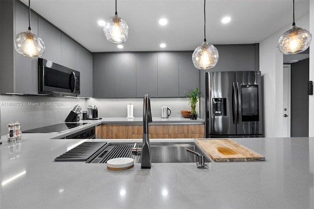 kitchen with gray cabinets, hanging light fixtures, and stainless steel appliances