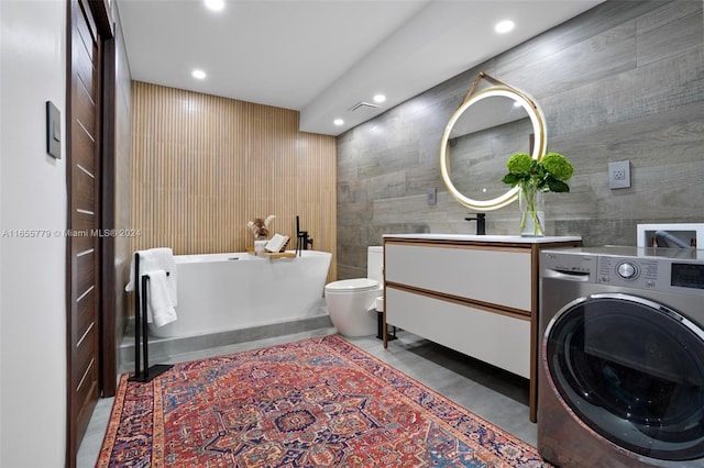 bathroom featuring washer / clothes dryer, toilet, a bathing tub, and vanity