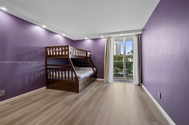 unfurnished bedroom featuring a wall of windows and light hardwood / wood-style floors