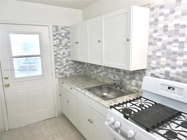 kitchen featuring white range with gas cooktop, sink, white cabinets, and decorative backsplash