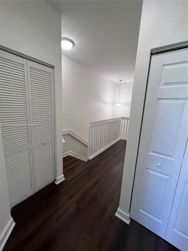 hall featuring baseboards, an upstairs landing, and dark wood finished floors