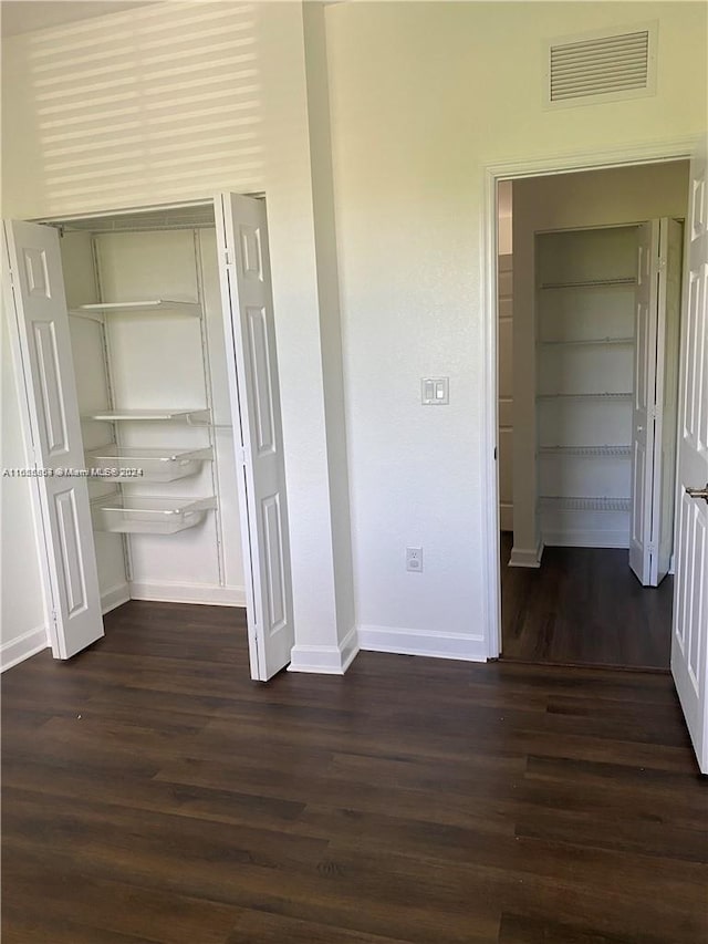 interior space with visible vents, baseboards, and dark wood-style floors