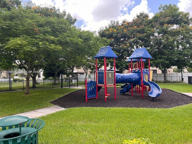 communal playground featuring a yard and fence