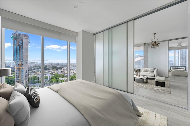 bedroom featuring multiple windows, floor to ceiling windows, a chandelier, and light hardwood / wood-style flooring