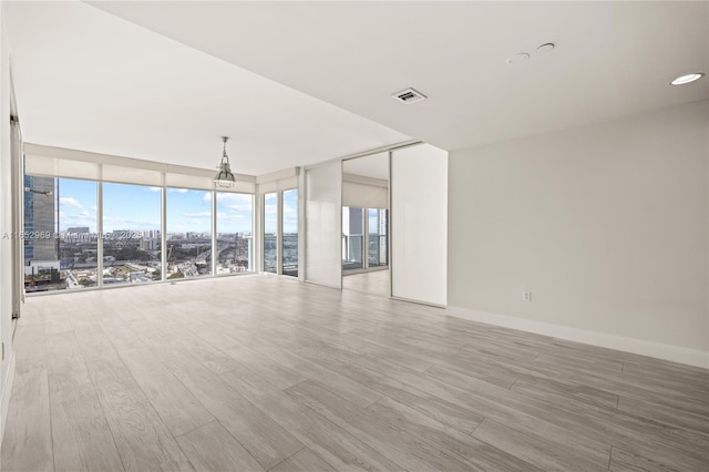 spare room with floor to ceiling windows, light hardwood / wood-style floors, and a wealth of natural light