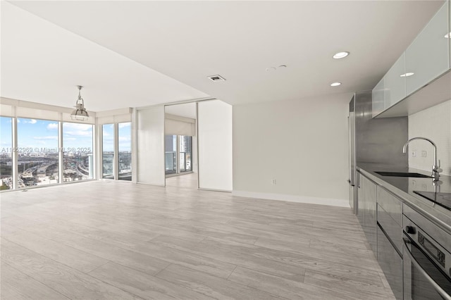 unfurnished living room featuring sink and light hardwood / wood-style flooring