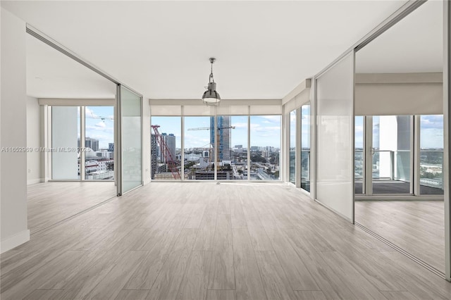 unfurnished room with floor to ceiling windows and light wood-type flooring