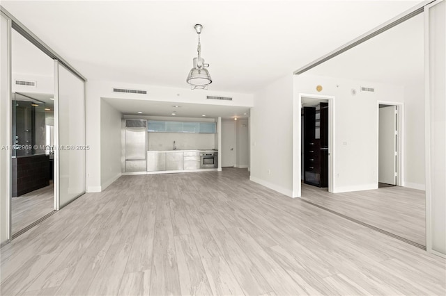 unfurnished living room with sink and light hardwood / wood-style flooring