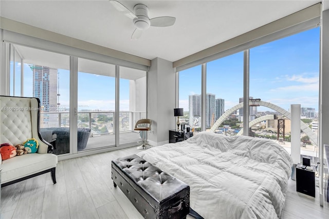 bedroom with ceiling fan, a wall of windows, multiple windows, and access to outside