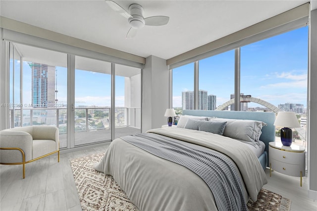 bedroom with expansive windows, ceiling fan, access to exterior, and multiple windows