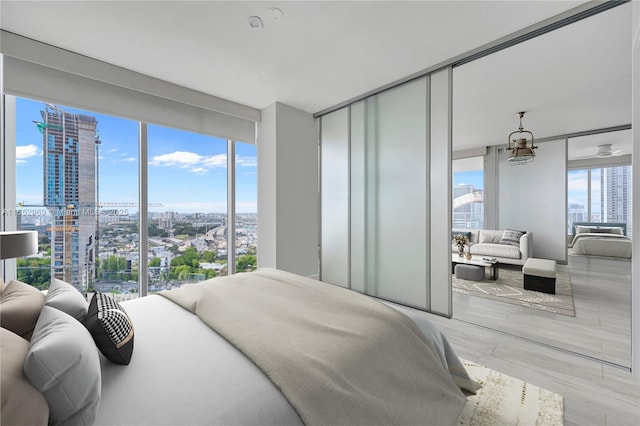 bedroom featuring multiple windows, floor to ceiling windows, and light wood-type flooring