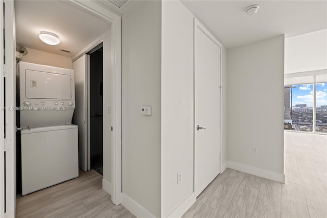 hallway with stacked washer / dryer and light wood-type flooring