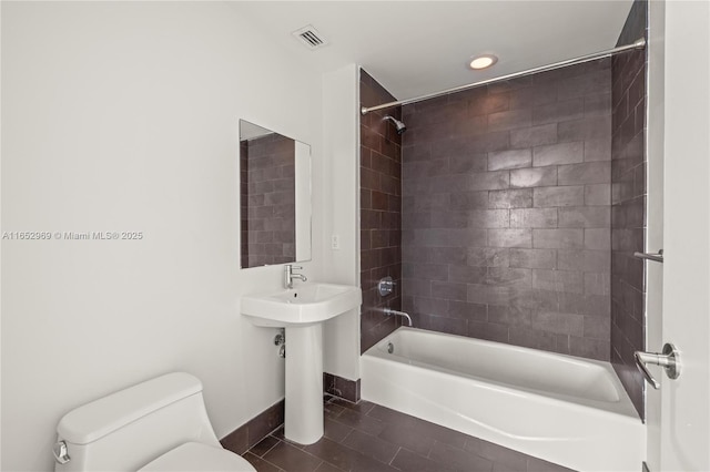 bathroom featuring tiled shower / bath combo, tile patterned floors, and toilet