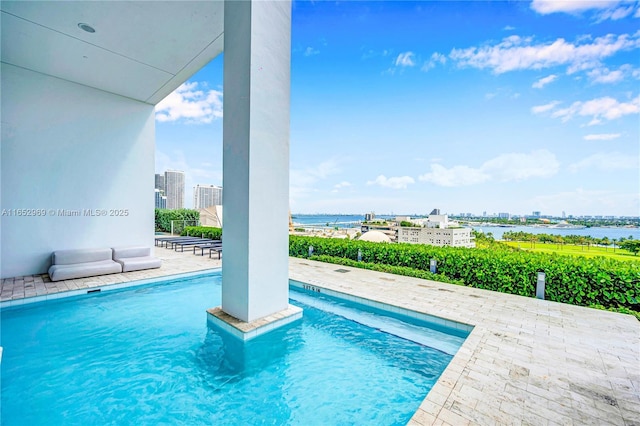 view of swimming pool featuring a water view and a patio