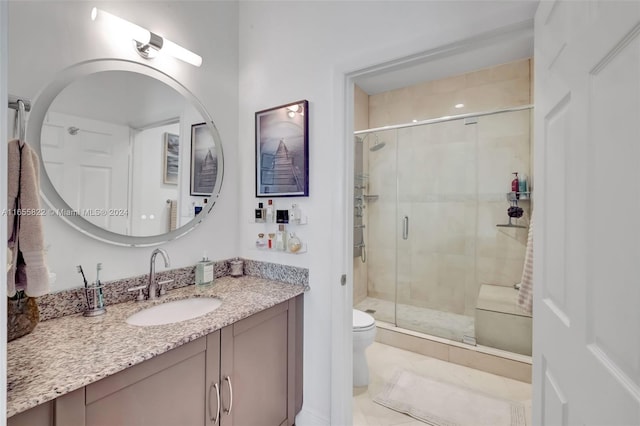 bathroom with vanity, toilet, tile patterned floors, and a shower with door