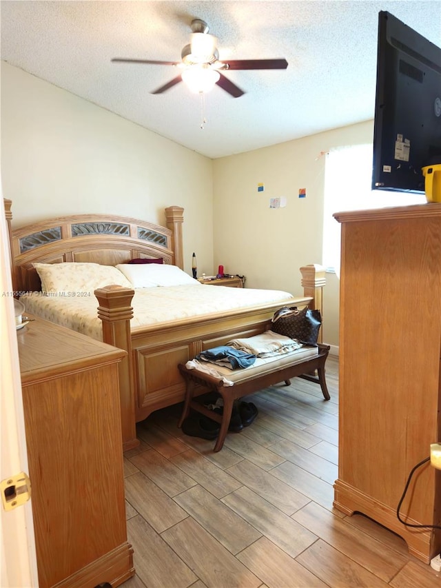 bedroom with light wood-type flooring, a textured ceiling, and ceiling fan